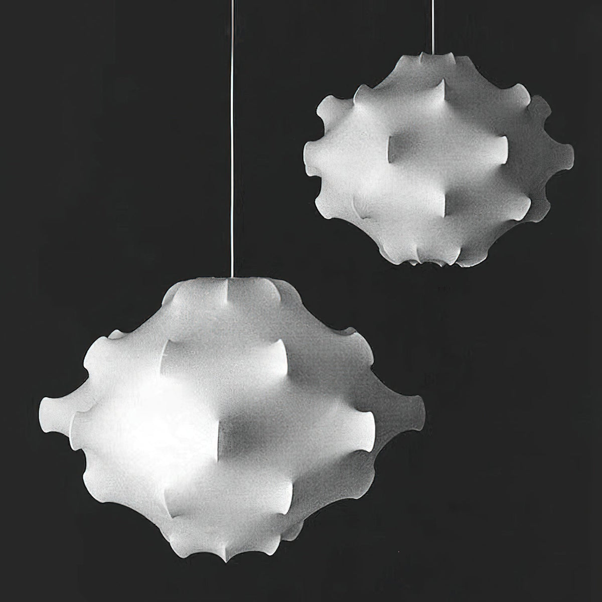 Black-and-white photo of two white Clérachic pendants of different sizes against a dark background.