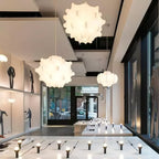 Several white Clérachic pendants glow in a long, bright shop interior with a tiled floor and glass front.