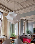 A white Clérachic pendant hangs beneath a decorated ceiling, with tall windows and a bright pink bench in the next room.