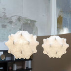 Two white Clérachic pendants glow side by side in front of a curved plaster wall with a shelf below.