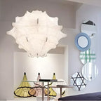 A large white Clérachic pendant hangs above a glass table with coloured shades, beside round striped mirrors.