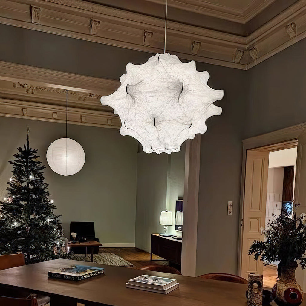 A white Clérachic pendant hangs in a grey-green room with ornate cornices, a Christmas tree and a wooden table.