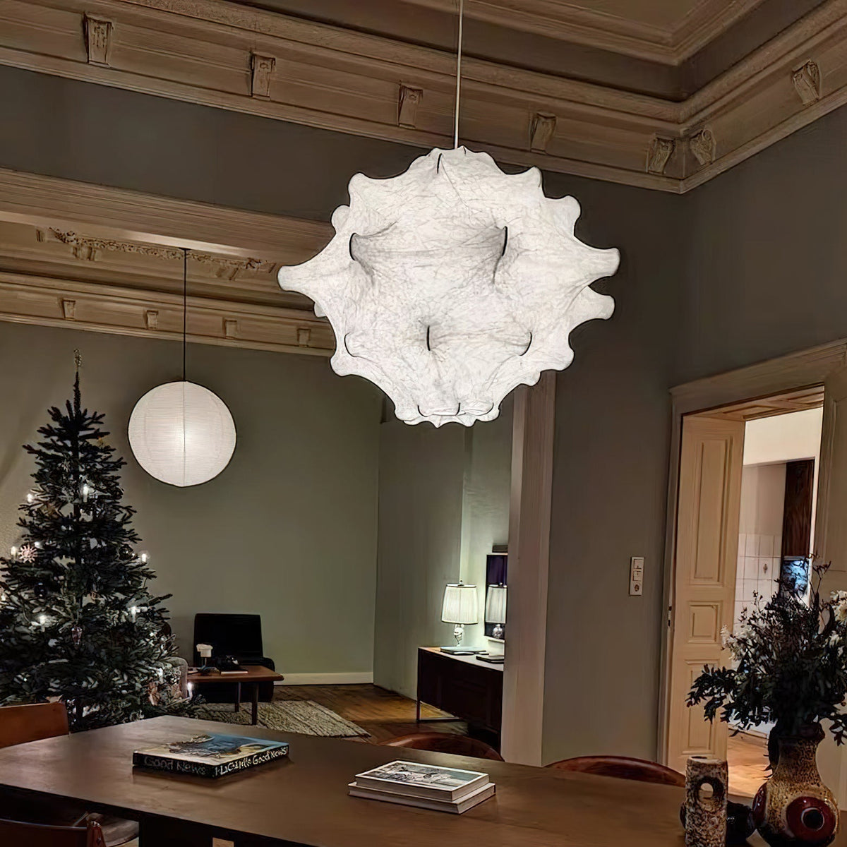 A white Clérachic pendant hangs in a grey-green room with ornate cornices, a Christmas tree and a wooden table.