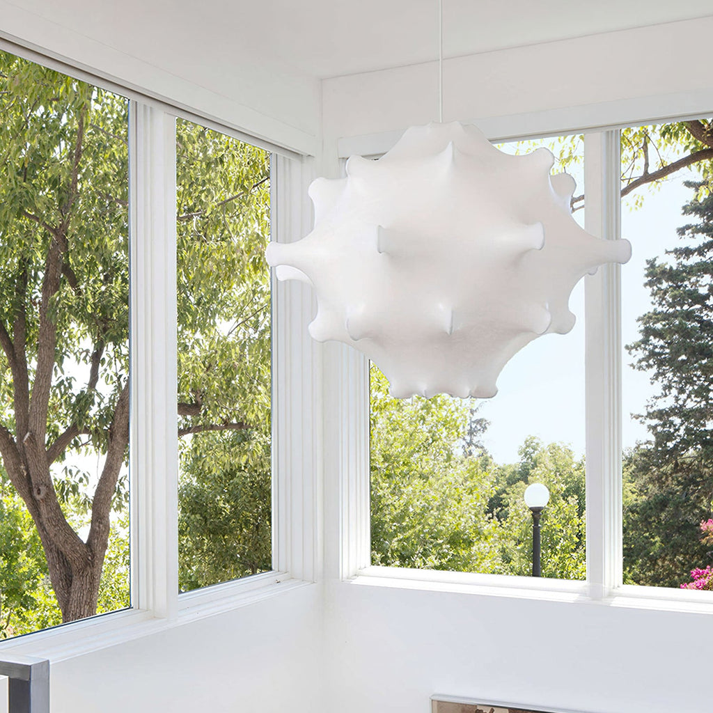A white Clérachic pendant hangs in front of tall windows, with trees and a lamp post outside.