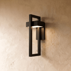 A Clérachic black steel wall light frames a white acrylic light bar within an open rectangular bracket on plaster.
