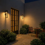 The same paneled entryway glows at night as both Clérachic steel wall lights light the door and boxwood planters.