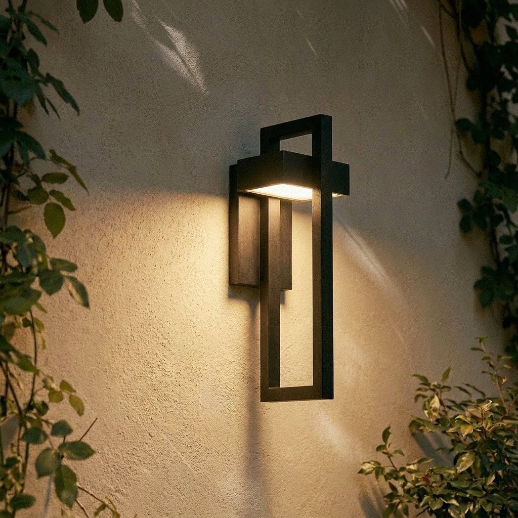 Close-up at dusk on the Clérachic steel wall light's layered black frame glowing against a rain-flecked wall.