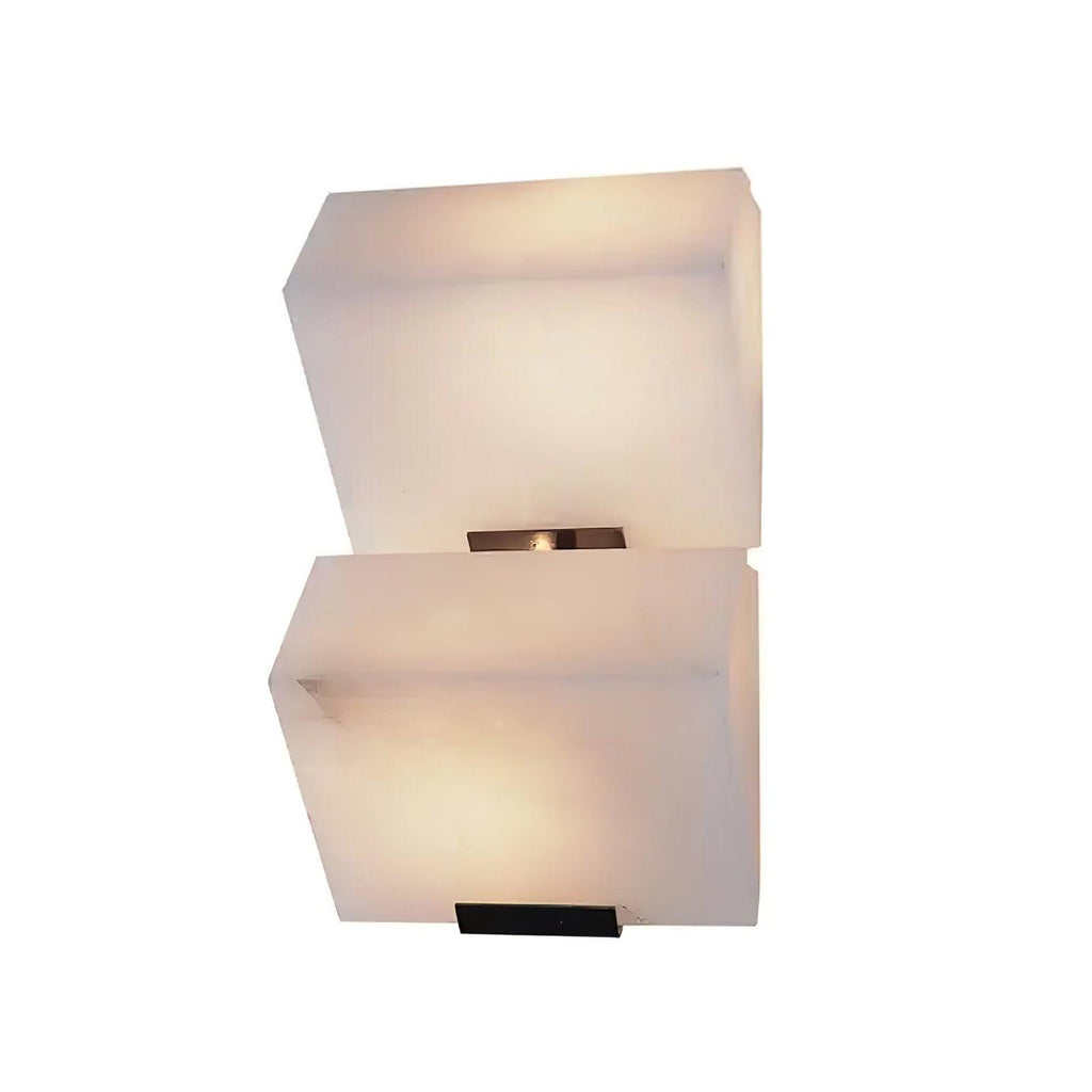 A larger view of a two-block Clérachic alabaster wall light, its stepped blocks glowing softly above black wall plates.