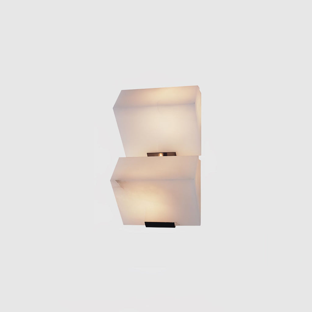 A two-block Clérachic alabaster wall light on a light grey backdrop, its stepped blocks lit softly from within.