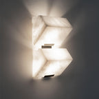 Close view of two stacked alabaster blocks of this Clérachic wall light glowing on a dark grey wall, with light spilling above and below.