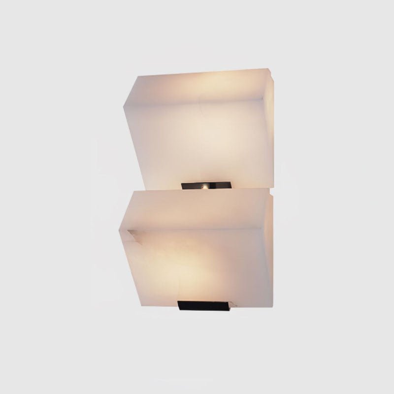 A two-block Clérachic alabaster wall light on a light grey backdrop, its stepped blocks glowing above black wall plates.