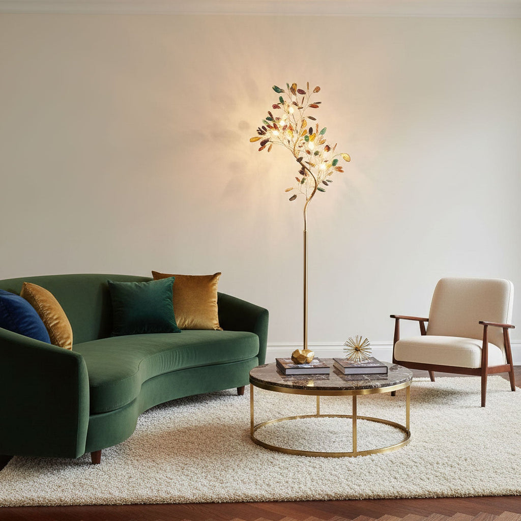 Lit Clérachic agate tree floor lamp beside a green velvet sofa, a round brass coffee table and a cream armchair.