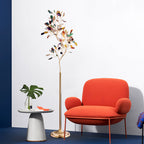 Clérachic agate floor lamp beside a bright orange armchair and a small white side table, against a white and blue wall.