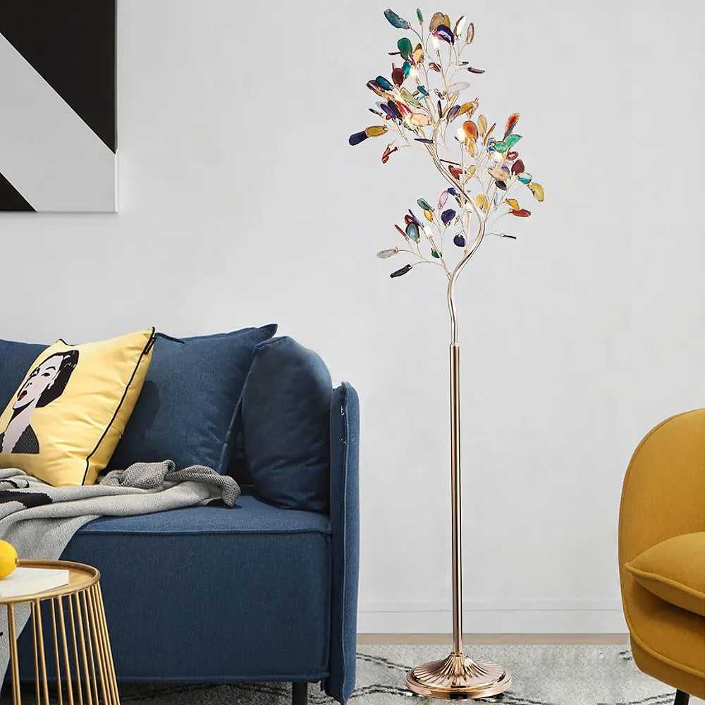Clérachic agate floor lamp beside a blue sofa with a yellow cushion, against a pale wall with a monochrome print.