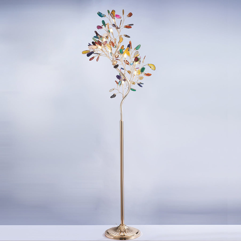Clérachic agate floor lamp on a pale blue-grey backdrop, its slices in many colours on a slim gold stem.