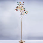 Clérachic agate floor lamp on a pale blue-grey backdrop, its slices in many colours on a slim gold stem.