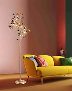 Lit Clérachic agate floor lamp against a coral-pink wall, beside a yellow sofa with pink and green cushions.