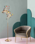 Lit Clérachic agate floor lamp beside a grey-brown armchair with gold legs, against a teal arched panel on a pink floor.