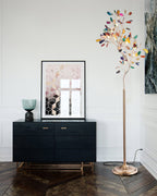 Clérachic agate floor lamp beside a black sideboard and a framed geometric print, on a dark wood herringbone floor.
