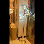 Clérachic agate floor lamp lit in a showroom corridor, its slices glowing on a gold stem and base.