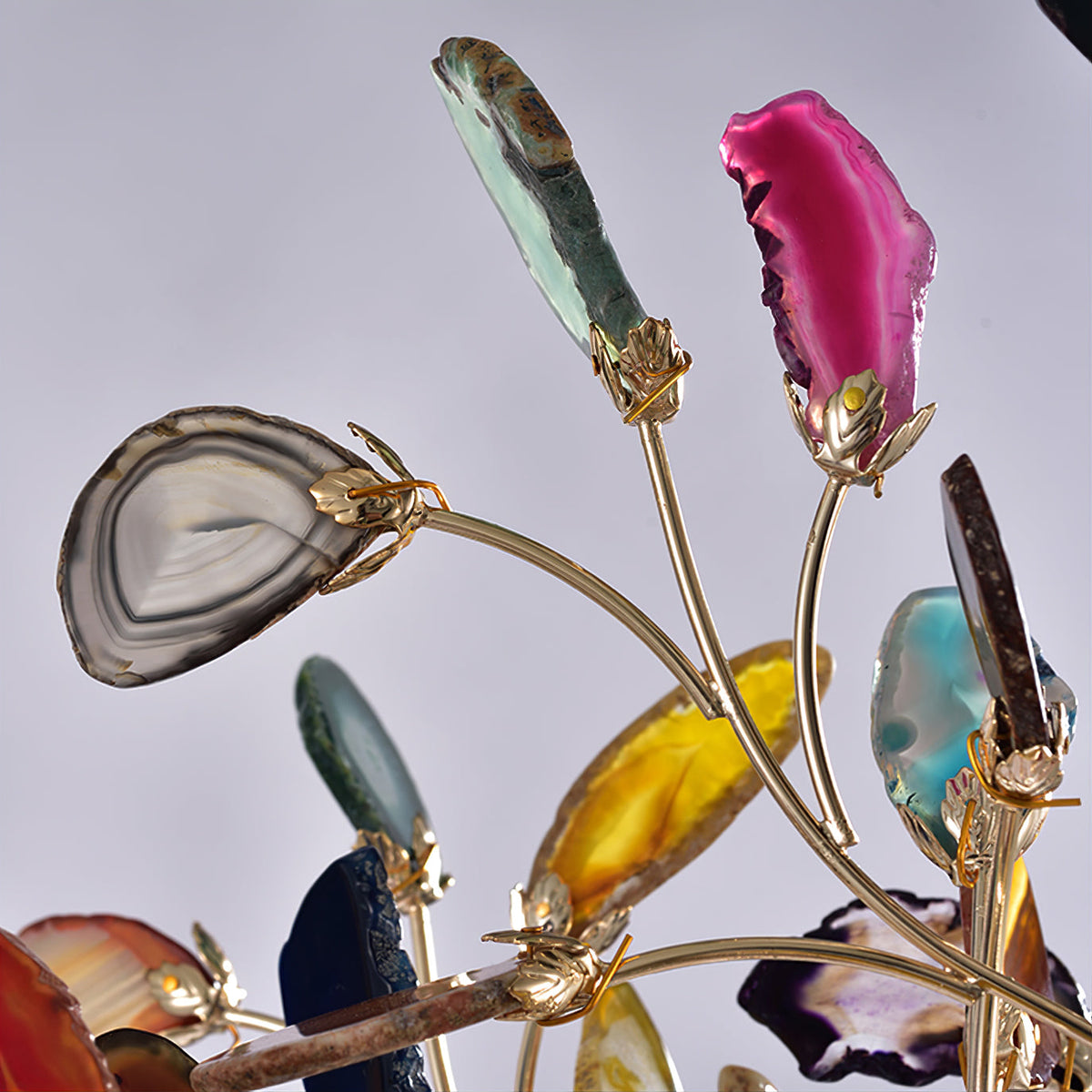 Close view of agate slices in pink, green, yellow and grey on gold clips and thin branches of this Clérachic floor lamp.