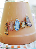 Agate slices wrapped in fine wire hanging from a terracotta pot, shown as a reference for the stone used in this Clérachic floor lamp.
