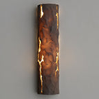 Dark brown textured wall light glowing amber through vertical cracks, mounted on a pale grey wall, from Clérachic.