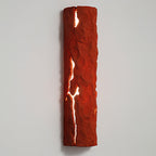 Red stone-look wall light with cracks glowing white, mounted on a pale grey wall, a Clérachic wall light.