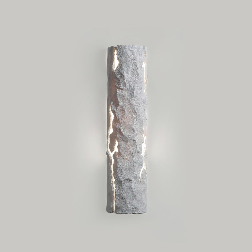 Pale grey stone-look wall light with soft light leaking from the cracks on a grey wall, from Clérachic.