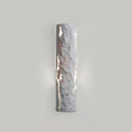 Pale grey stone-look wall light with soft light leaking from the cracks on a grey wall, from Clérachic.