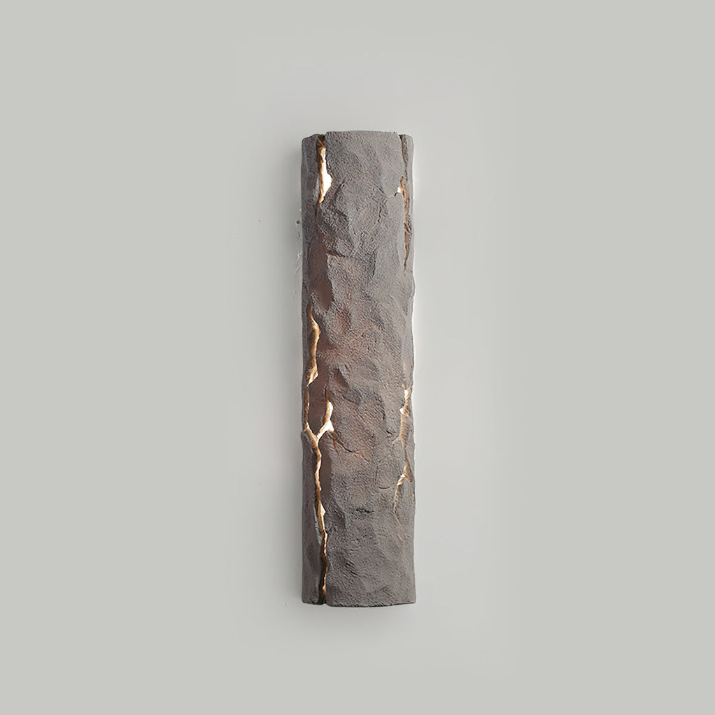 Taupe-grey stone-look wall light lit softly through cracks on a pale grey wall, from Clérachic.