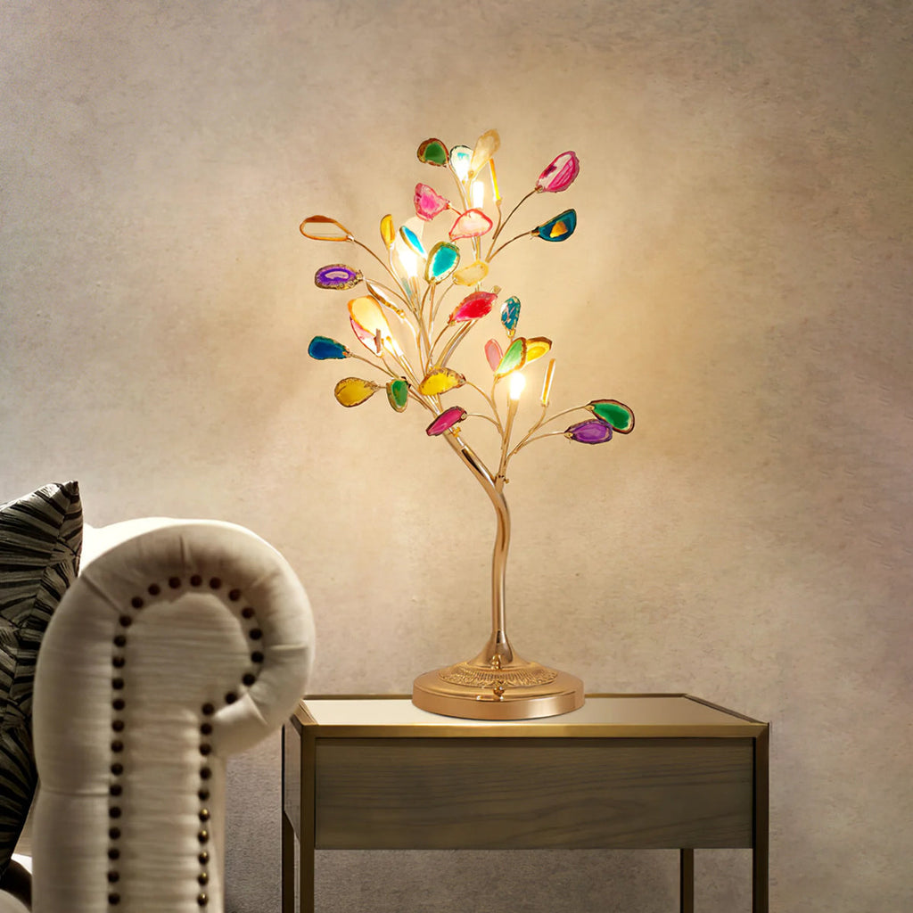 Warm bulbs light the coloured agate slices of this Clérachic table lamp, set on a small side table by a studded armchair.