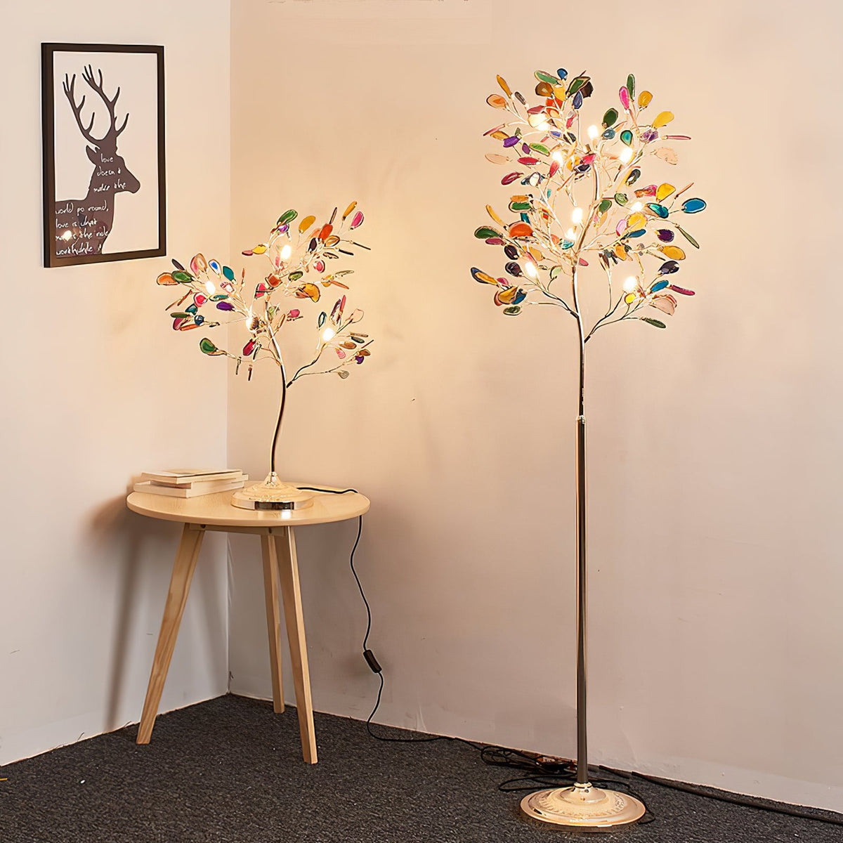 Corner of a room with the Clérachic table lamp on a round wooden side table and a taller floor version of the same tree beside it.