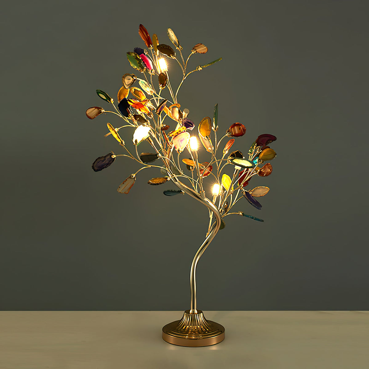 Against a dark olive wall, this Clérachic table lamp lights its agate leaves, with a gold-toned stem and a fluted round base.