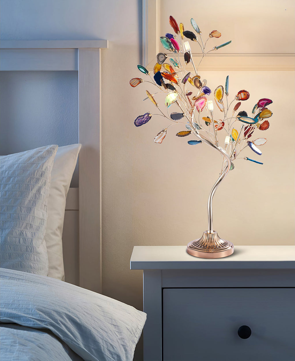 Agate slices in many colours cover the branches of this Clérachic table lamp, standing on a pale blue bedside cabinet.