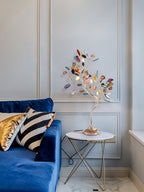 Smaller in the frame, this Clérachic table lamp sits on a round glass table by a blue velvet sofa and panelled wall.