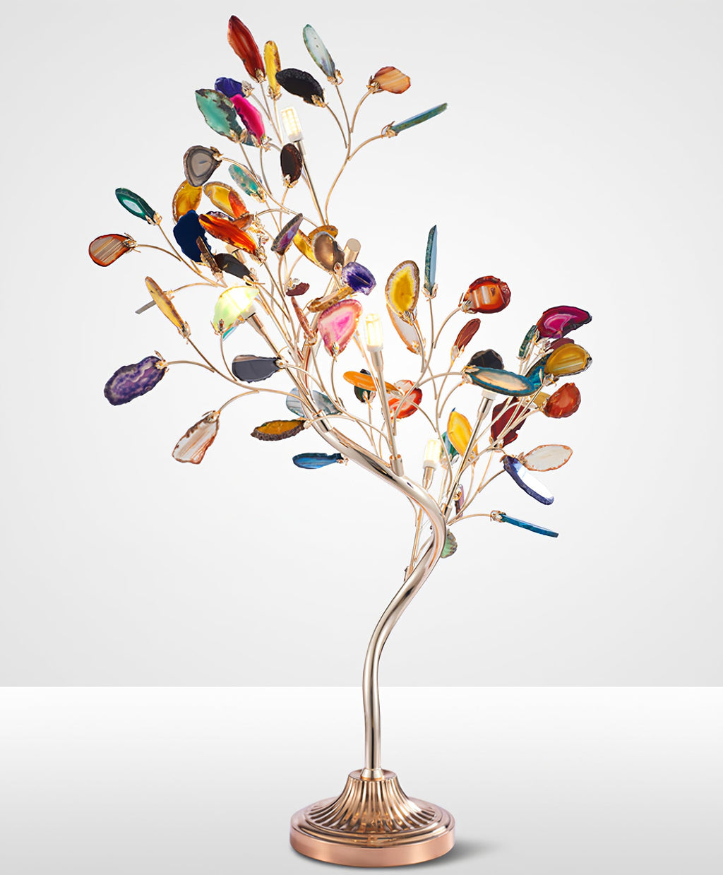Studio view of the Clérachic table lamp, with branching stems of coloured agate leaves above a fluted bronze base.