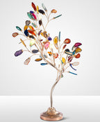 Studio view of the Clérachic table lamp, with branching stems of coloured agate leaves above a fluted bronze base.