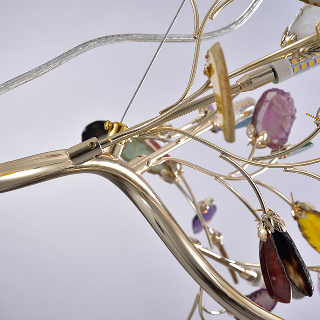 Close view of the gold-toned branches, bulb holders and a hanging agate slice on this Clérachic table lamp.