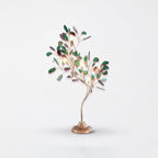 This Clérachic table lamp carries green agate leaves, with warm bulbs showing among the branches, against pale grey.