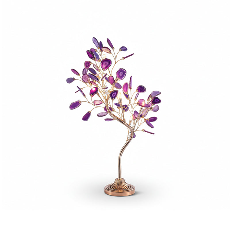 A Clérachic table lamp in purple agate leaves, with bulbs glowing between the branches, on a white backdrop.