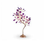 A Clérachic table lamp in purple agate leaves, with bulbs glowing between the branches, on a white backdrop.