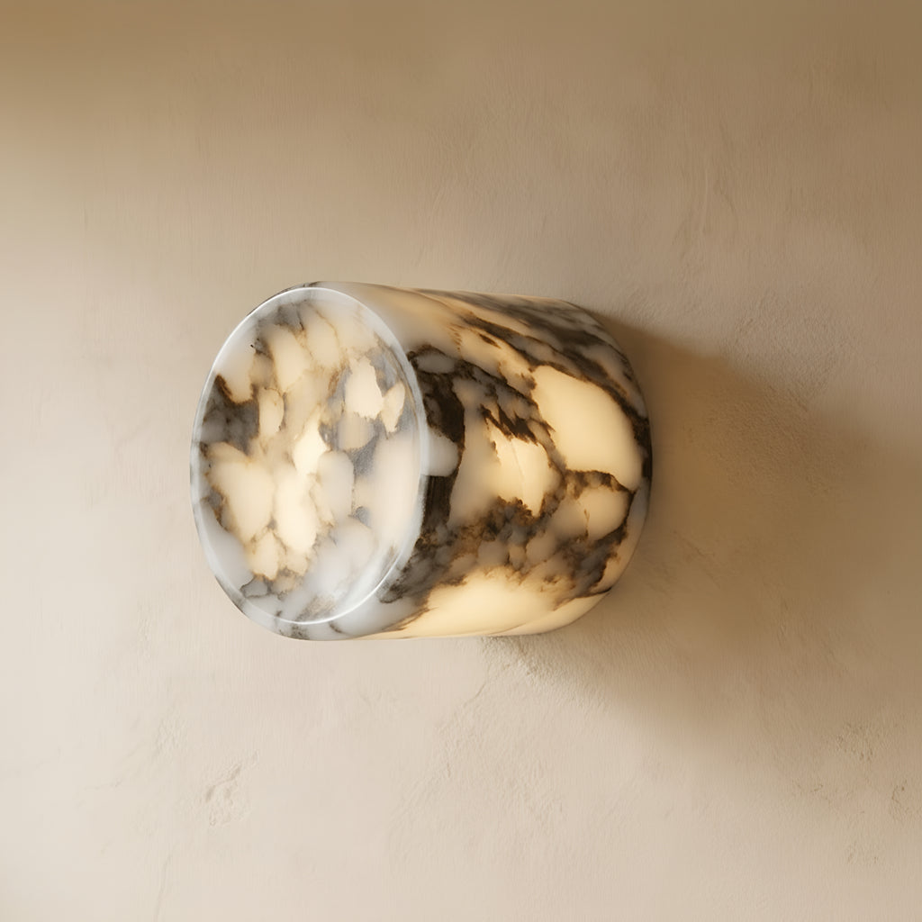 Clérachic stone wall light lit warm on a plaster wall, the veining glowing amber through the translucent stone