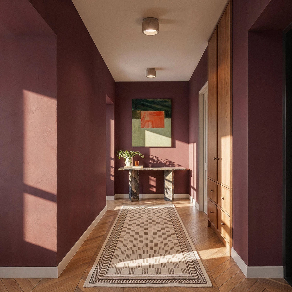 Clérachic two small drum ceiling lights lit warm along a plum-walled hallway with a marble console and herringbone floor.