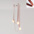 The Strap-Hung Glass Globe Pendant Light in red canvas, Clérachic's three-head version with globes staggered at different drop heights beside a fabric swatch.