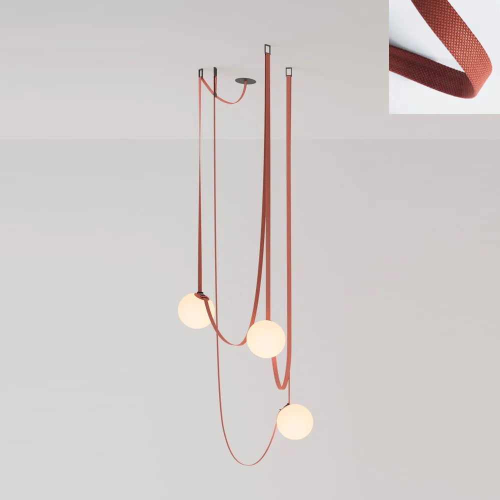 The Strap-Hung Glass Globe Pendant Light in red canvas, Clérachic's three-head version with globes staggered at different drop heights beside a fabric swatch.