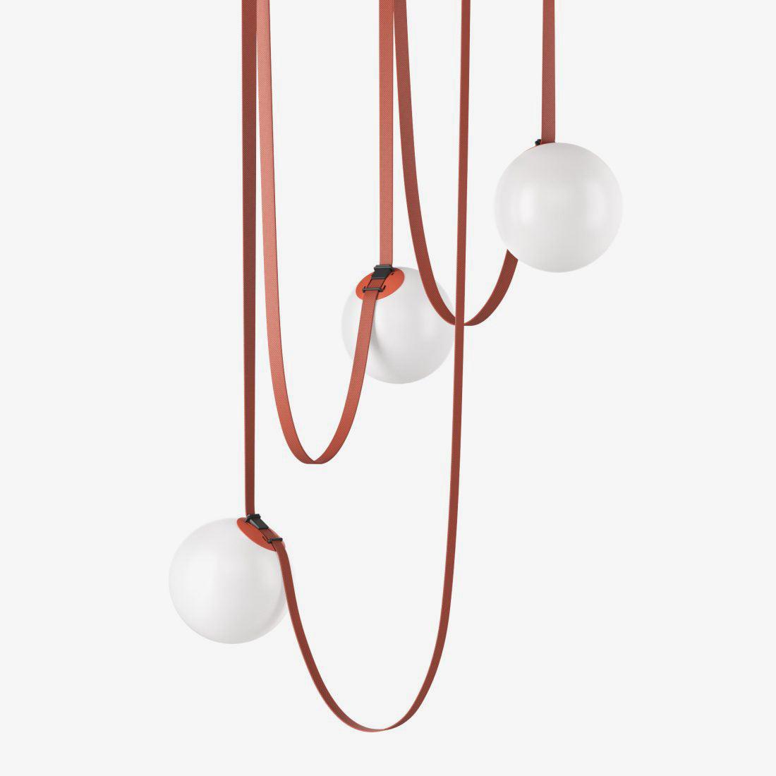 Close detail of the Clérachic Strap-Hung Glass Globe Pendant Light's red canvas straps crossing above three glass globes at different drop heights.
