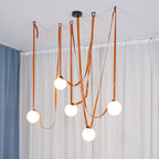Another full-room angle of the Clérachic Strap-Hung Glass Globe Pendant Light in orange leather, straps crossing above a curtained living area.