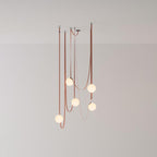 Studio view of the Clérachic Strap-Hung Glass Globe Pendant Light in a rust-toned canvas, its globes staggered at three different drop heights.
