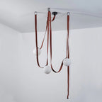 Small vignette of the Clérachic Strap-Hung Glass Globe Pendant Light's three-head version, its brick-red straps looping to globes at different heights.